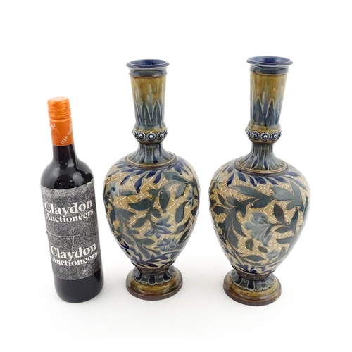 107 - A pair of Doulton Lambeth stoneware vases with  floral and foliate decoration. Marked under,  bearin... 
