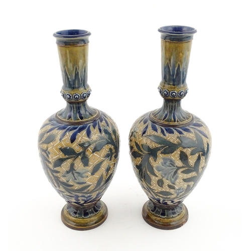 107 - A pair of Doulton Lambeth stoneware vases with  floral and foliate decoration. Marked under,  bearin... 