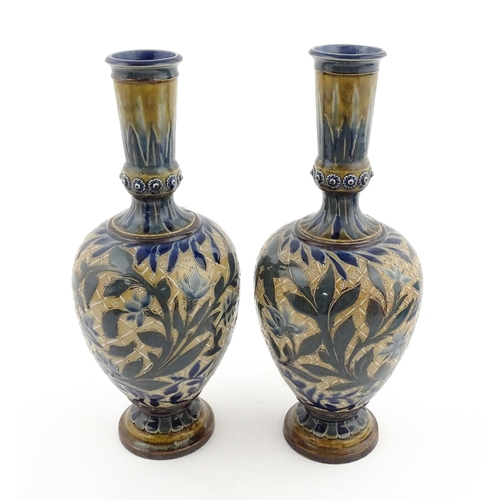 107 - A pair of Doulton Lambeth stoneware vases with  floral and foliate decoration. Marked under,  bearin... 