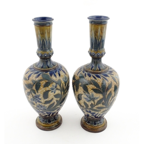 107 - A pair of Doulton Lambeth stoneware vases with  floral and foliate decoration. Marked under,  bearin... 