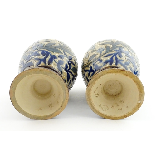 107 - A pair of Doulton Lambeth stoneware vases with  floral and foliate decoration. Marked under,  bearin... 