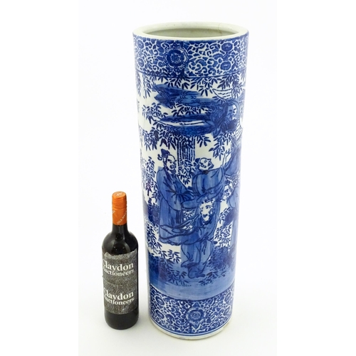 30 - A Chinese blue and white umbrella / stick stand decorated with figures and bamboo. Approx. 24 1/4