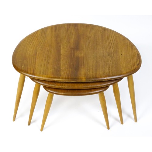 1666 - Vintage / Retro: An Ercol elm nest of three graduated 'pebble' tables raised on turned tapering legs... 
