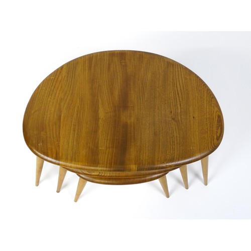 1666 - Vintage / Retro: An Ercol elm nest of three graduated 'pebble' tables raised on turned tapering legs... 
