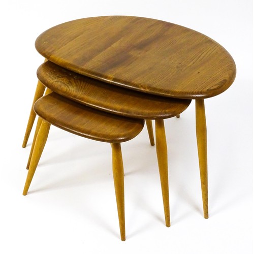 1666 - Vintage / Retro: An Ercol elm nest of three graduated 'pebble' tables raised on turned tapering legs... 