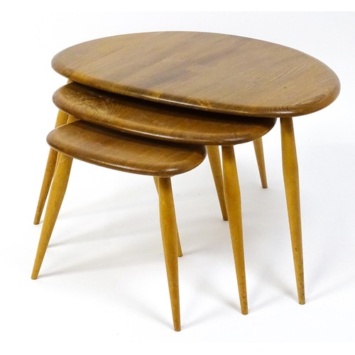 1666 - Vintage / Retro: An Ercol elm nest of three graduated 'pebble' tables raised on turned tapering legs... 