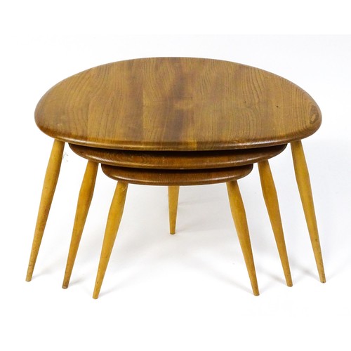 1666 - Vintage / Retro: An Ercol elm nest of three graduated 'pebble' tables raised on turned tapering legs... 