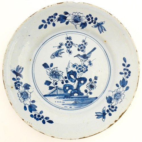 68 - A Delft blue and white plate decorated in the Chinese style with taihu rock, birds, flowers and foli... 