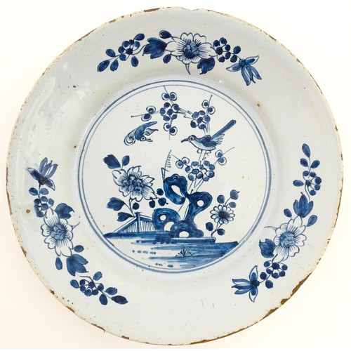 68 - A Delft blue and white plate decorated in the Chinese style with taihu rock, birds, flowers and foli... 