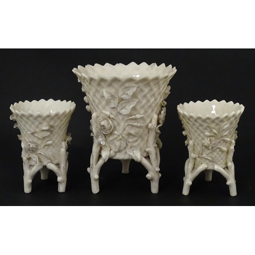 99 - Three Belleek Flowered Spill vases of basket form with floral and foliate decoration and raised on t... 