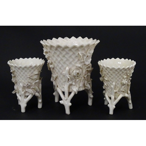99 - Three Belleek Flowered Spill vases of basket form with floral and foliate decoration and raised on t... 