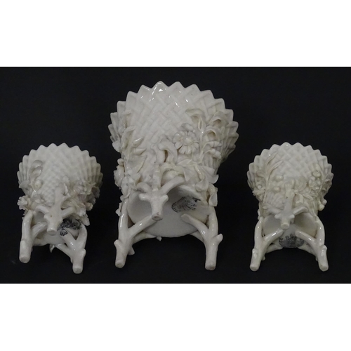 99 - Three Belleek Flowered Spill vases of basket form with floral and foliate decoration and raised on t... 