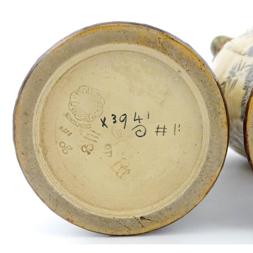 104 - A pair of Doulton Lambeth stoneware grotesque ewers / pitchers, the bodies decorated with carp fish ... 