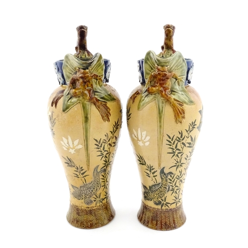 104 - A pair of Doulton Lambeth stoneware grotesque ewers / pitchers, the bodies decorated with carp fish ... 