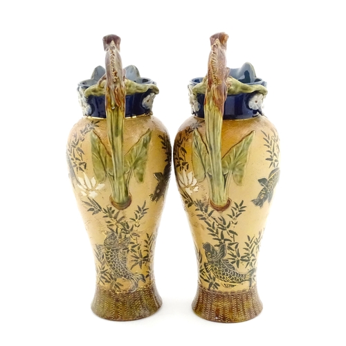 104 - A pair of Doulton Lambeth stoneware grotesque ewers / pitchers, the bodies decorated with carp fish ... 