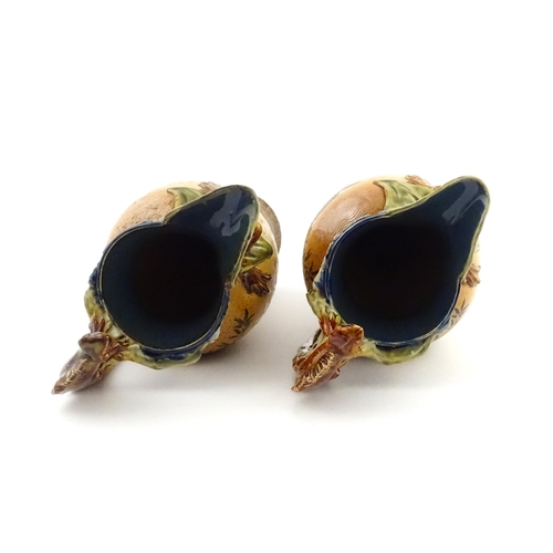 104 - A pair of Doulton Lambeth stoneware grotesque ewers / pitchers, the bodies decorated with carp fish ... 