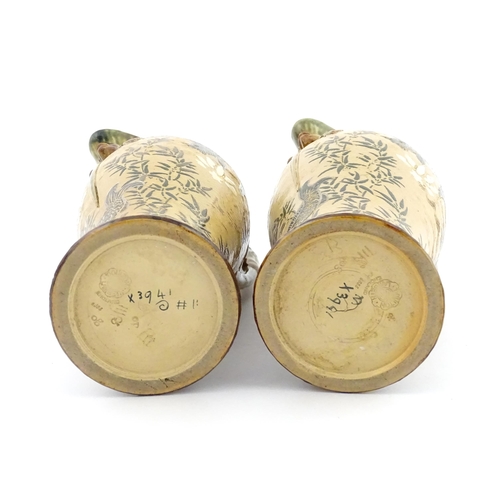 104 - A pair of Doulton Lambeth stoneware grotesque ewers / pitchers, the bodies decorated with carp fish ... 