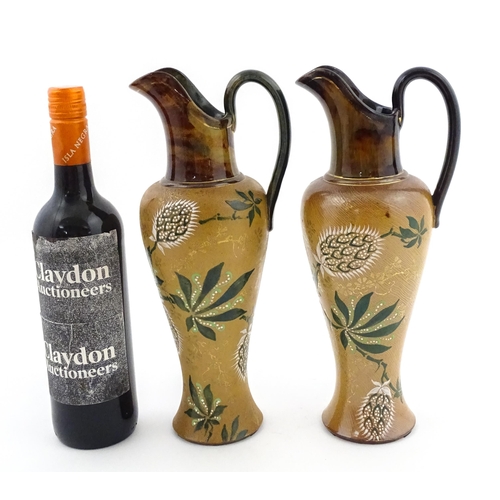 105 - A pair of Doulton Lambeth ewers / pitchers with stylised floral and foliate decoration by Lizzie Mar... 