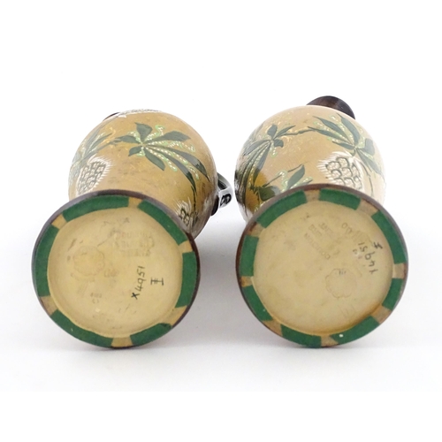 105 - A pair of Doulton Lambeth ewers / pitchers with stylised floral and foliate decoration by Lizzie Mar... 