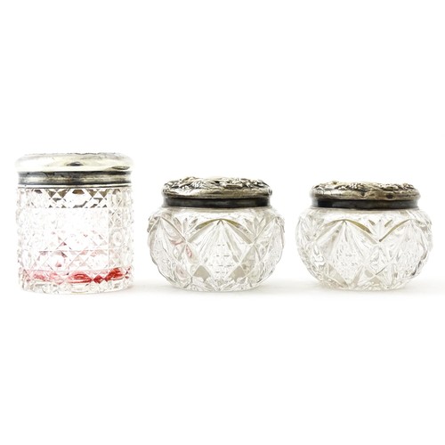 381 - A pair of cut glass dressing table pots with silver lids. Together with another. (3)