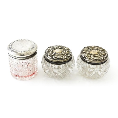 381 - A pair of cut glass dressing table pots with silver lids. Together with another. (3)