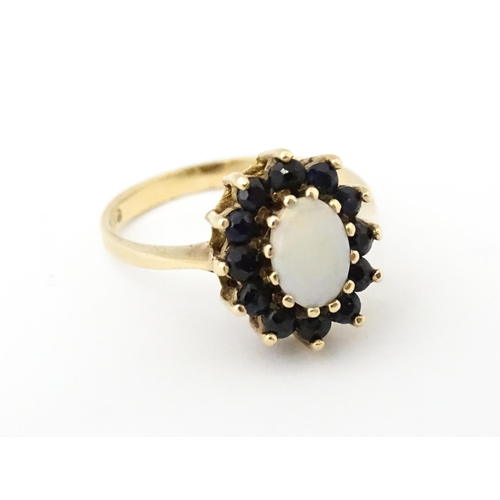 517 - A 9ct gold ring set with central opal bordered by blue spinels. Ring size approx. M