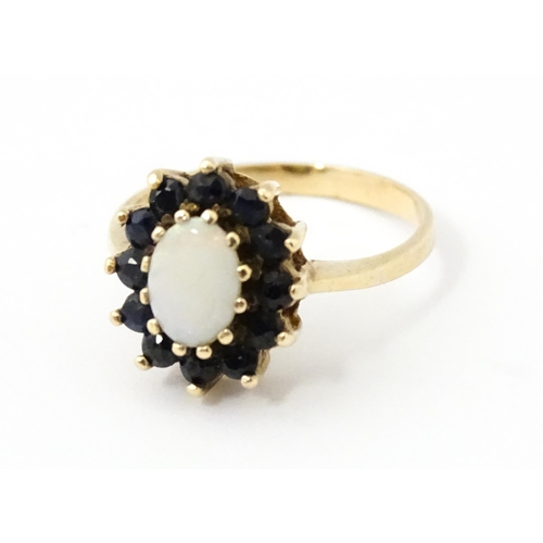 517 - A 9ct gold ring set with central opal bordered by blue spinels. Ring size approx. M