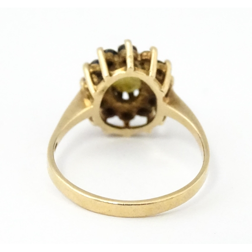 517 - A 9ct gold ring set with central opal bordered by blue spinels. Ring size approx. M