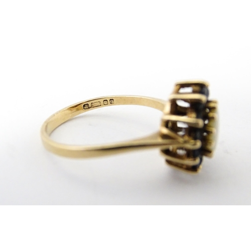 517 - A 9ct gold ring set with central opal bordered by blue spinels. Ring size approx. M