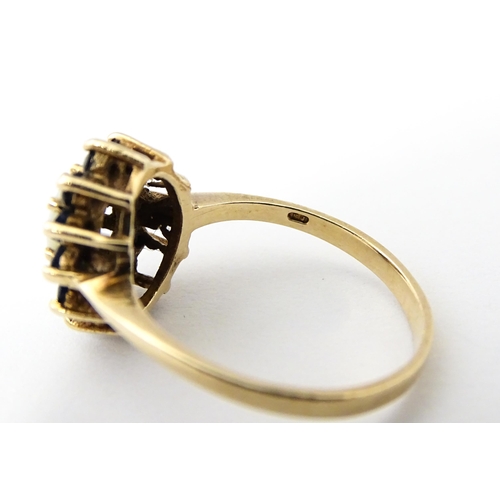 517 - A 9ct gold ring set with central opal bordered by blue spinels. Ring size approx. M