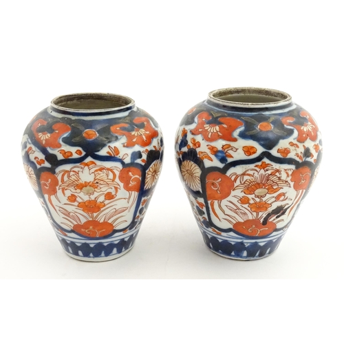 66 - A pair of Japanese vases decorated in the Imari palette decorated with flowers and foliage. Together... 