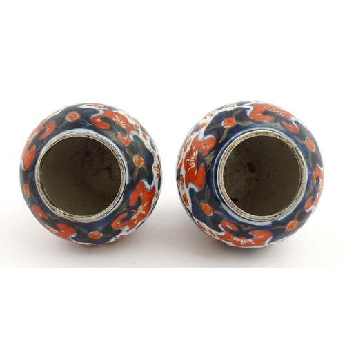 66 - A pair of Japanese vases decorated in the Imari palette decorated with flowers and foliage. Together... 