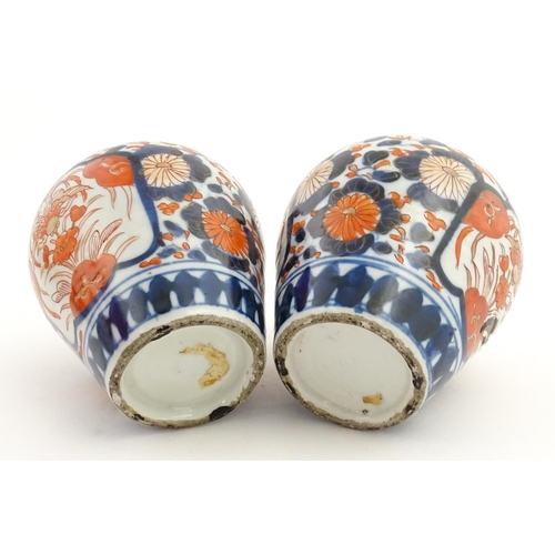 66 - A pair of Japanese vases decorated in the Imari palette decorated with flowers and foliage. Together... 