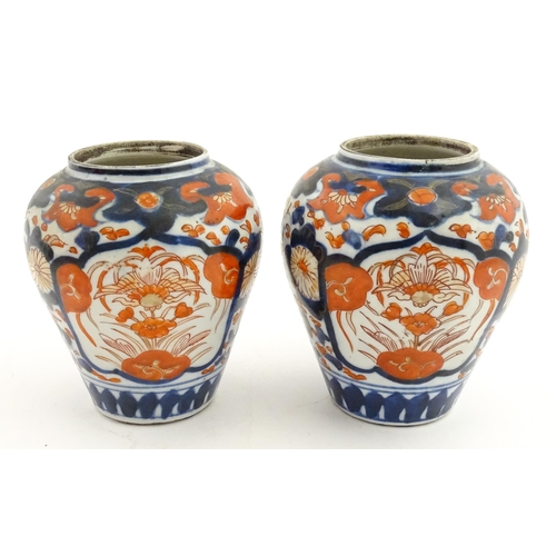 66 - A pair of Japanese vases decorated in the Imari palette decorated with flowers and foliage. Together... 