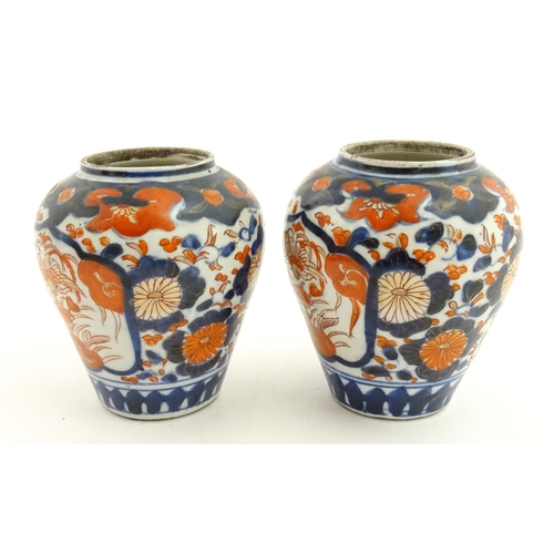 66 - A pair of Japanese vases decorated in the Imari palette decorated with flowers and foliage. Together... 