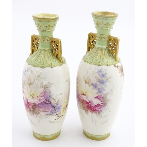 79 - A pair of Royal Bonn vases this twin gilt handles, decorated with hand painted flowers and foliage. ... 