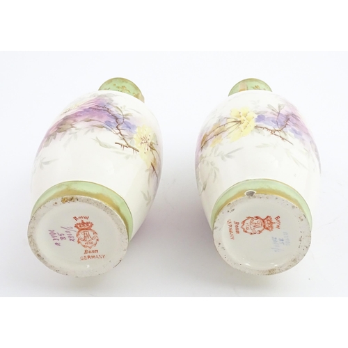 79 - A pair of Royal Bonn vases this twin gilt handles, decorated with hand painted flowers and foliage. ... 