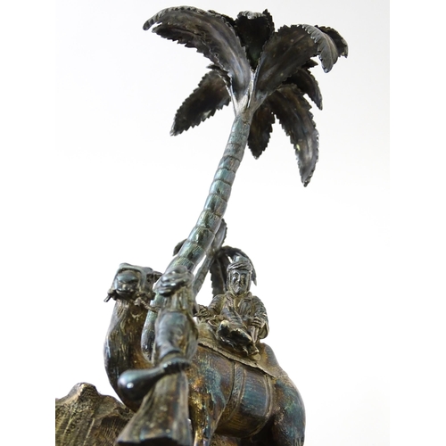 371 - A Victorian silver plate inkstand modelled as a man riding a camel with an attendant below two palm ... 
