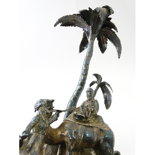 371 - A Victorian silver plate inkstand modelled as a man riding a camel with an attendant below two palm ... 