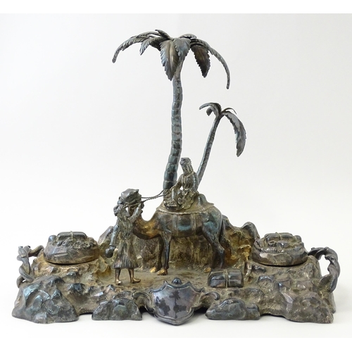 371 - A Victorian silver plate inkstand modelled as a man riding a camel with an attendant below two palm ... 