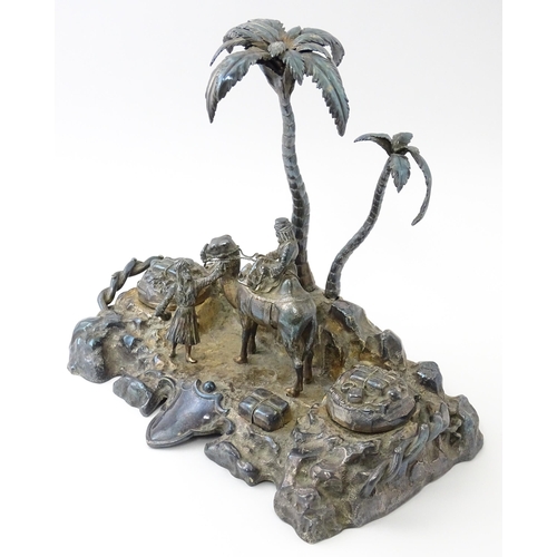 371 - A Victorian silver plate inkstand modelled as a man riding a camel with an attendant below two palm ... 