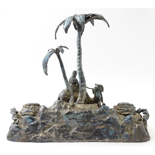 371 - A Victorian silver plate inkstand modelled as a man riding a camel with an attendant below two palm ... 