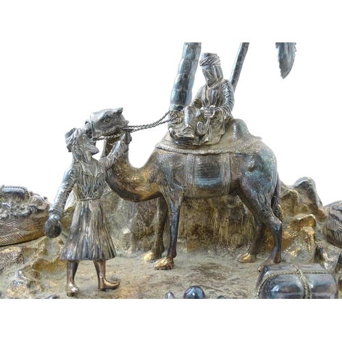 371 - A Victorian silver plate inkstand modelled as a man riding a camel with an attendant below two palm ... 