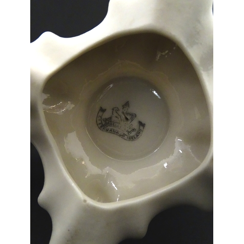 85 - A pair of Belleek jugs of shaped form with scrolling foliate decoration and green highlights. Both m... 