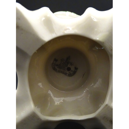 85 - A pair of Belleek jugs of shaped form with scrolling foliate decoration and green highlights. Both m... 