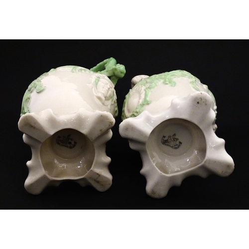 85 - A pair of Belleek jugs of shaped form with scrolling foliate decoration and green highlights. Both m... 