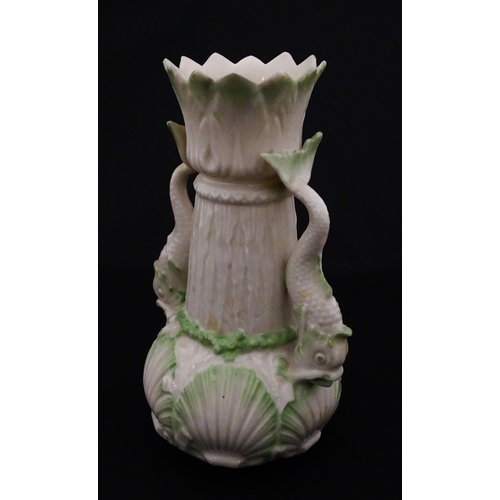 87 - A Belleek dolphin spill vase with twin fish handles and shell detail to base. Marked with Second Per... 