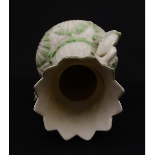 87 - A Belleek dolphin spill vase with twin fish handles and shell detail to base. Marked with Second Per... 