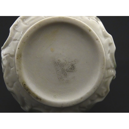 87 - A Belleek dolphin spill vase with twin fish handles and shell detail to base. Marked with Second Per... 