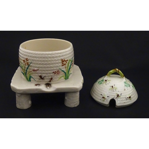 94 - A Belleek honey pot on stand of skep / beehive form decorated with bees, flowers and shamrocks. Rais... 